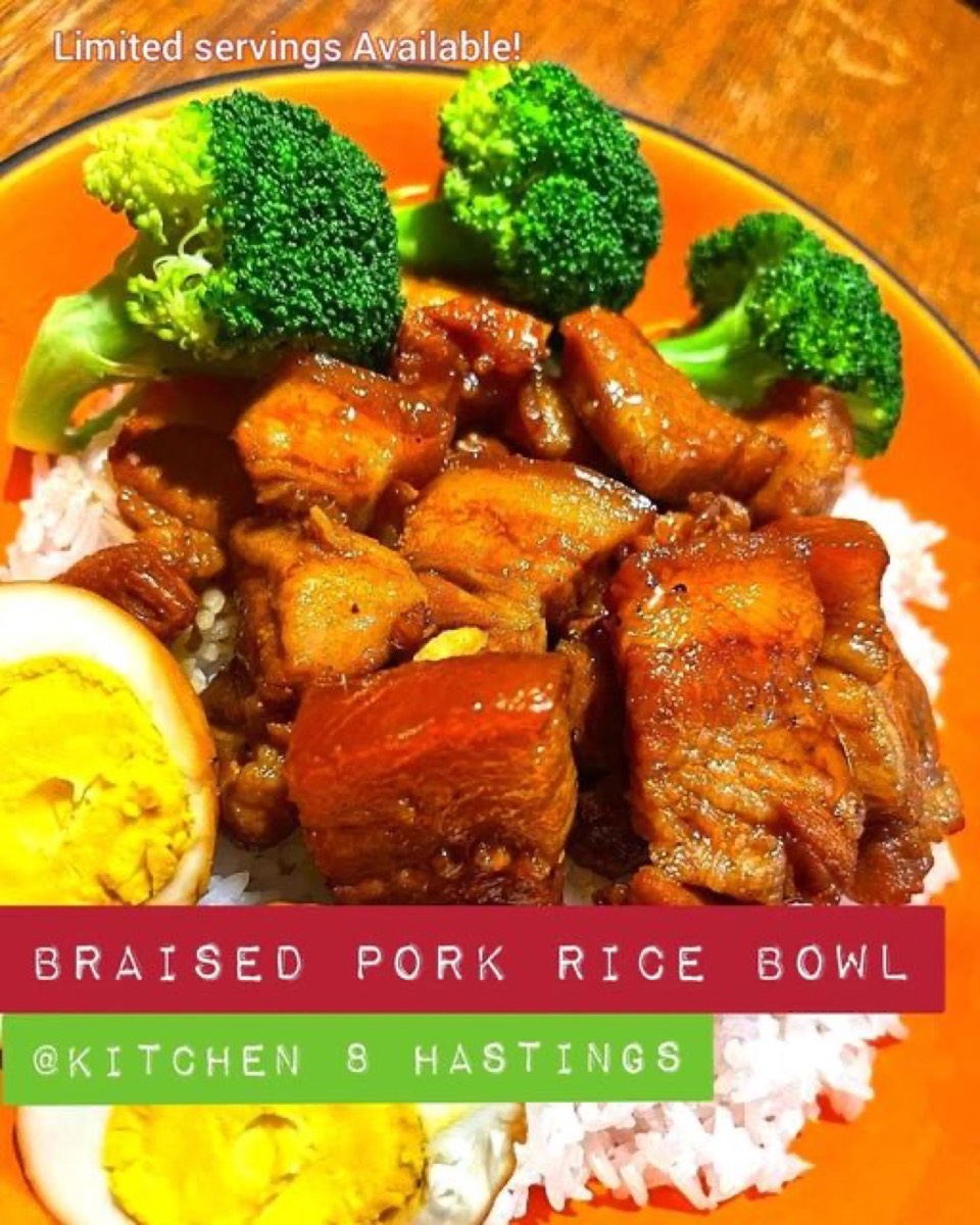 Braised pork belly pieces and broccoli on rice in an orange bowl, with half an egg at the side